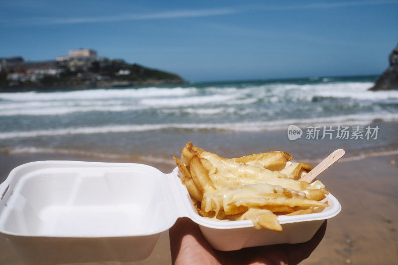 6月一个阳光明媚的日子，在康沃尔纽基的托万海滩(Towan Beach)买一盒芝士薯条。